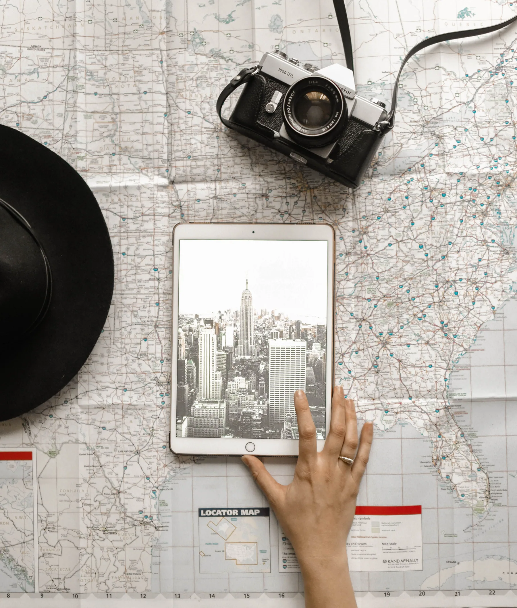 A camera and a tablet displaying the New York skyline on a paper map.
