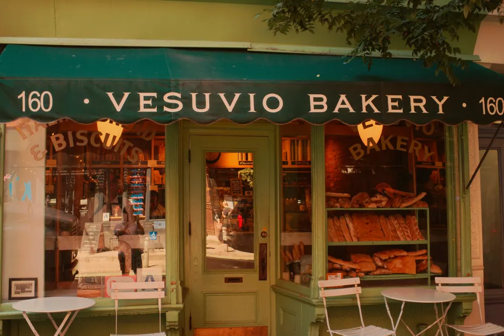 The green Vesuvio Bakery storefront with loaves of bread displayed in its window.
